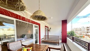 Un balcon avec une table en bois, un panier de fruits et un banc.