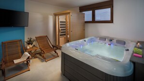 A room with a hot tub, two wooden chairs, a television, and a wooden cabinet. - Malibu Eclipse (Vir)