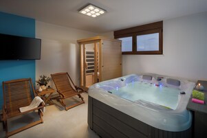 Une pièce équipée d’un jacuzzi, de deux chaises en bois, d’une télévision et d’un meuble en bois.