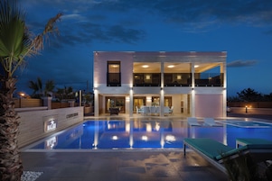 Un hôtel moderne à deux étages, doté d’une piscine, d’un espace extérieur aménagé et d’une entrée bien éclairée.