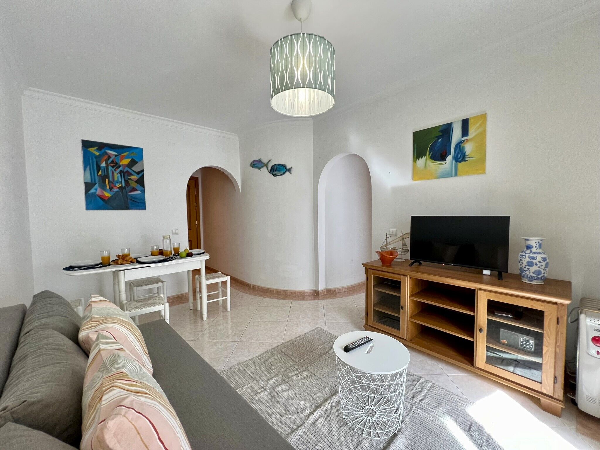 A modern living room with a sofa, dining table, TV, and decorative items.