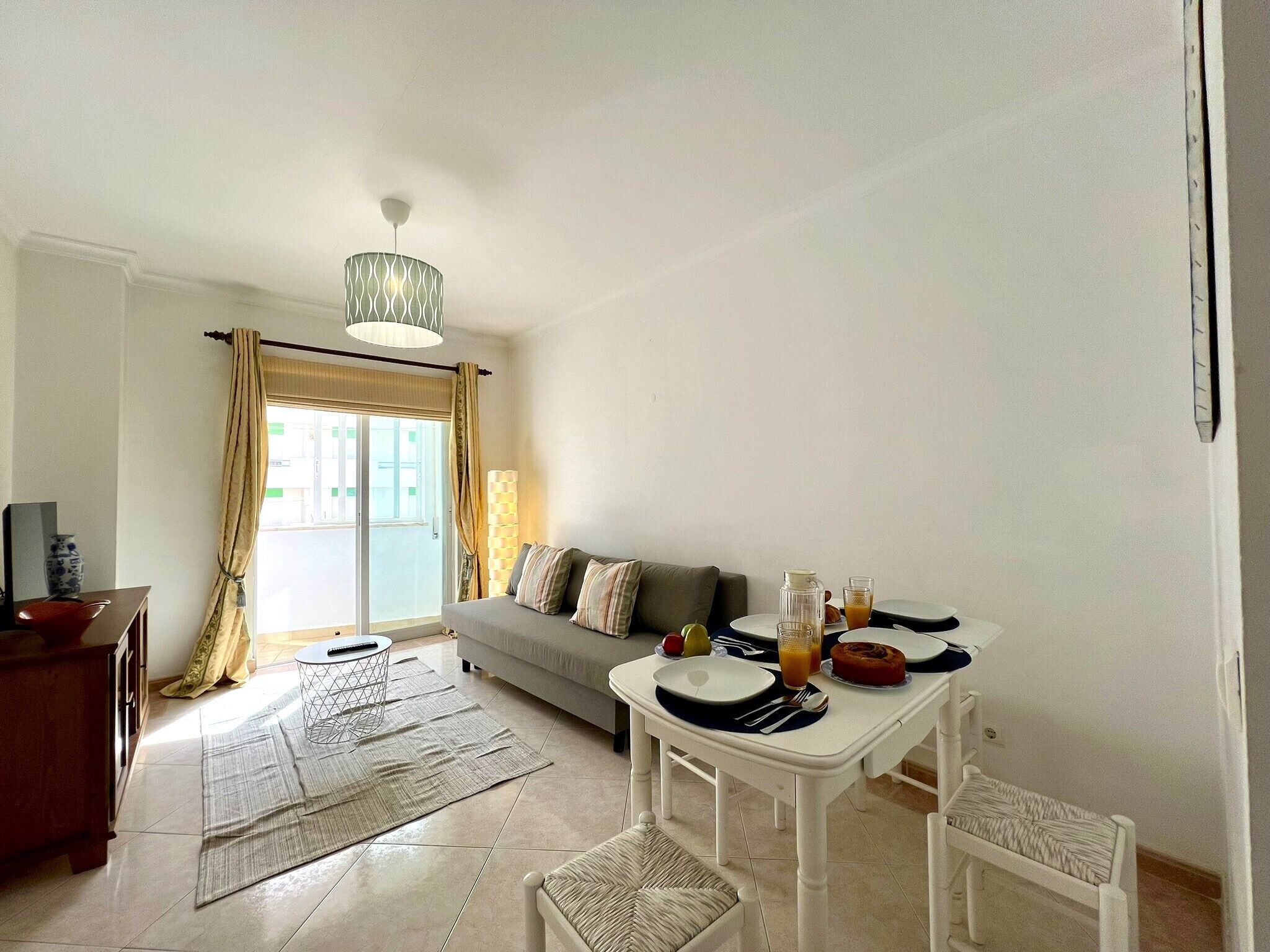 Un salón moderno con sofá, mesa de comedor y vistas al exterior.