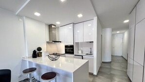 A modern kitchen with white cabinetry, a central island with stools, and a sleek design. - Albufeira Twins 3 With Pool by Homing (Albufeira)