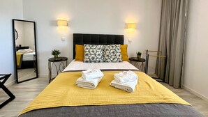 A hotel room with a large bed, two bedside tables, a mirror, and a window with curtains. - Albufeira Twins 3 With Pool by Homing (Albufeira)