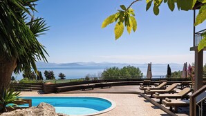 Area piscina con lettini e vista sul mare.