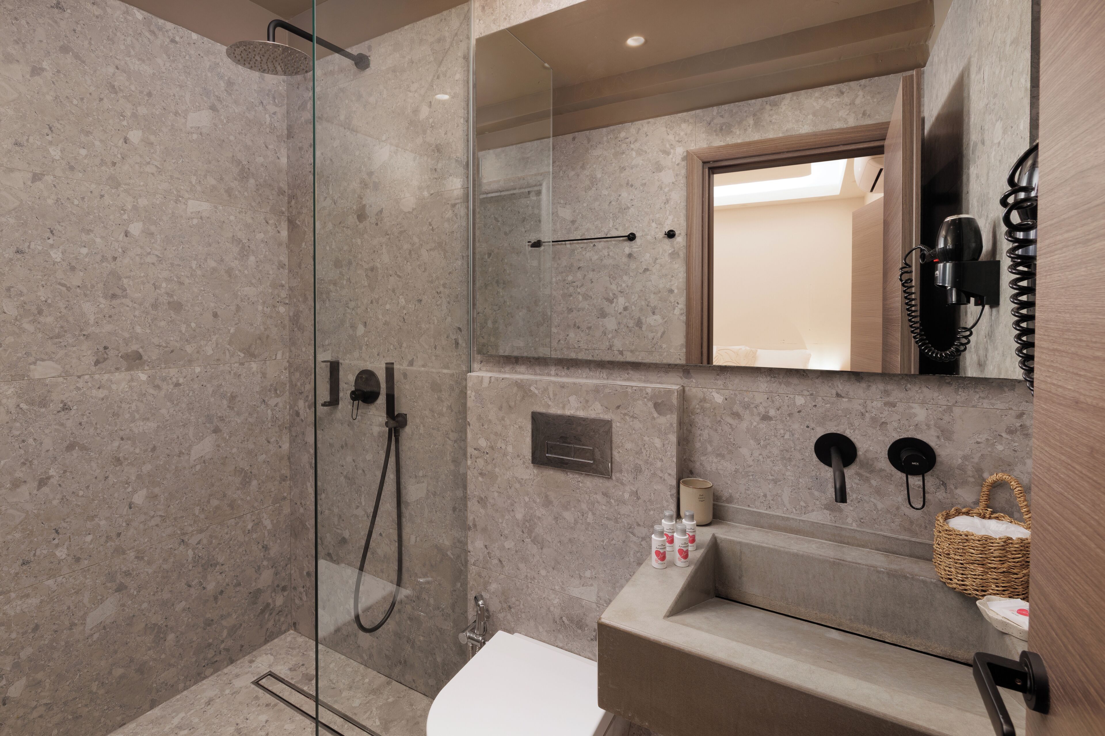 Ein modernes Badezimmer mit einer Glaskabine zur Dusche, einem großen Spiegel, einem Waschbecken und einem Telefon.