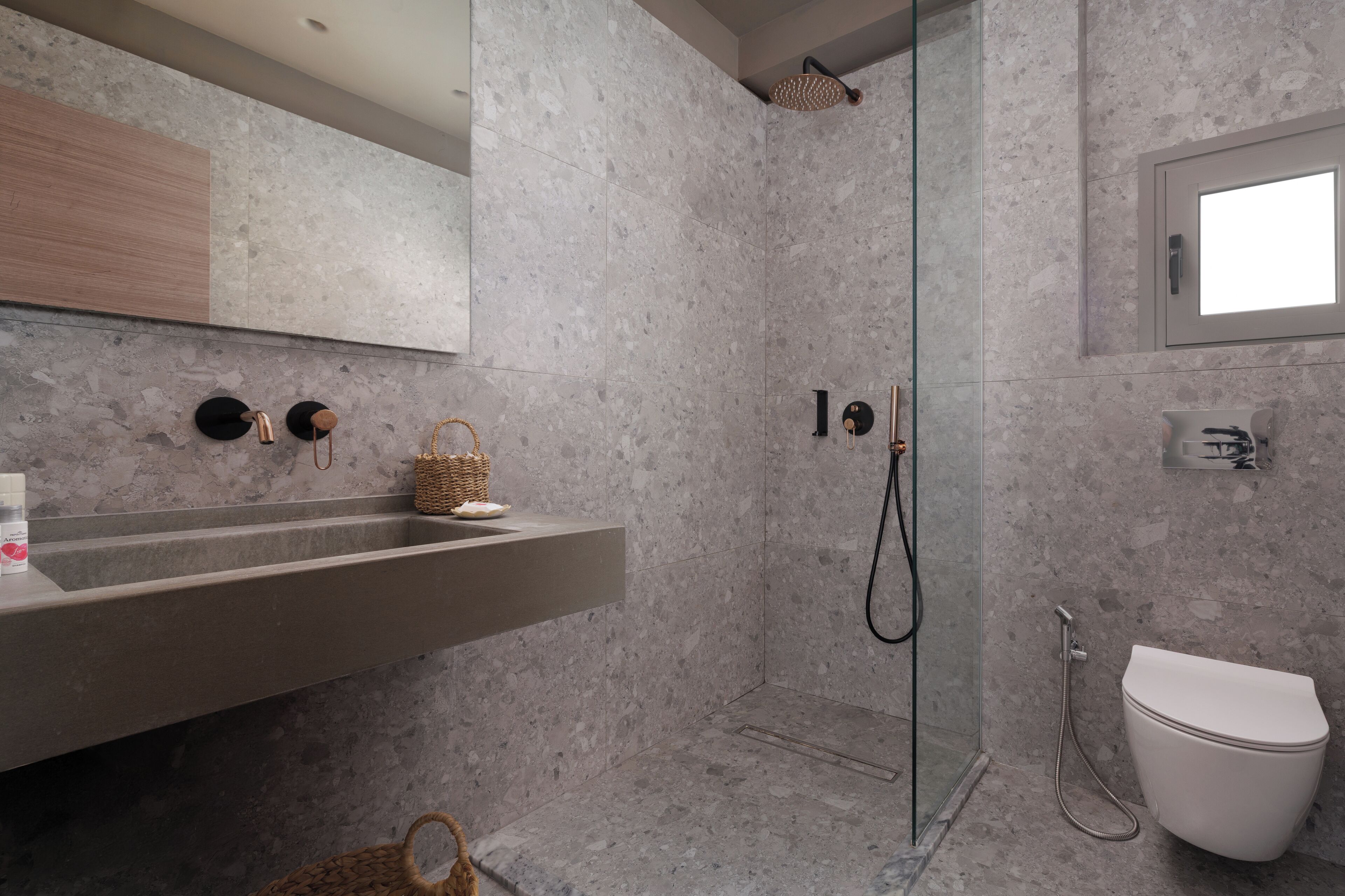 A modern bathroom with a glass-enclosed shower, a white toilet, and a marble-tiled wall.