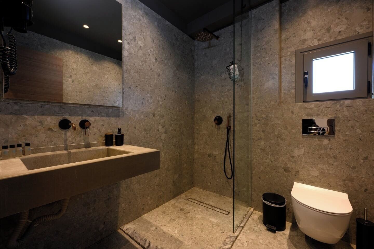 A modern bathroom with a large sink, a shower, and a toilet.