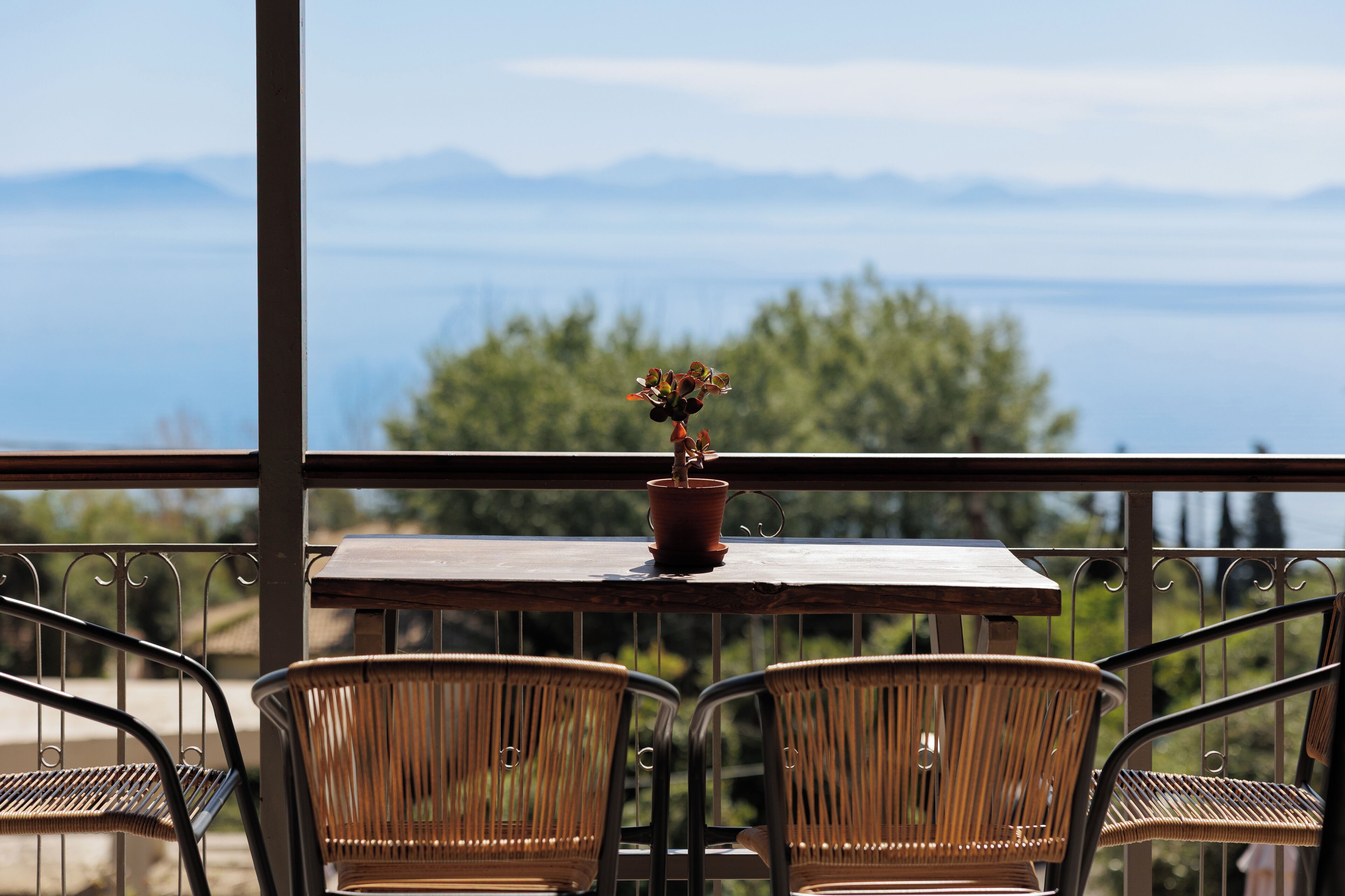 Un balcon avec des fauteuils en osier, une table en bois et une plante en pot.