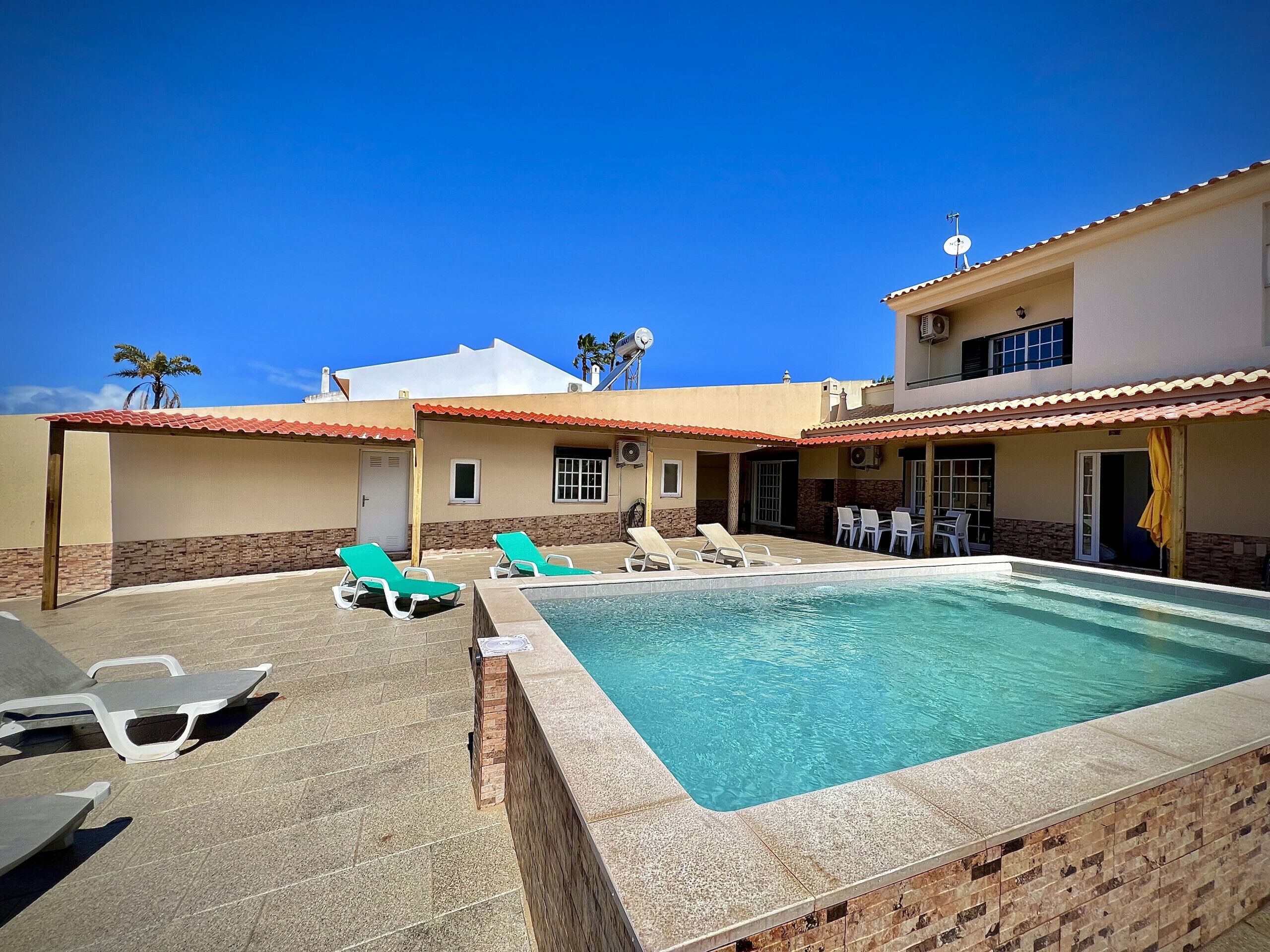 A pool area with lounge chairs and a clear blue pool.