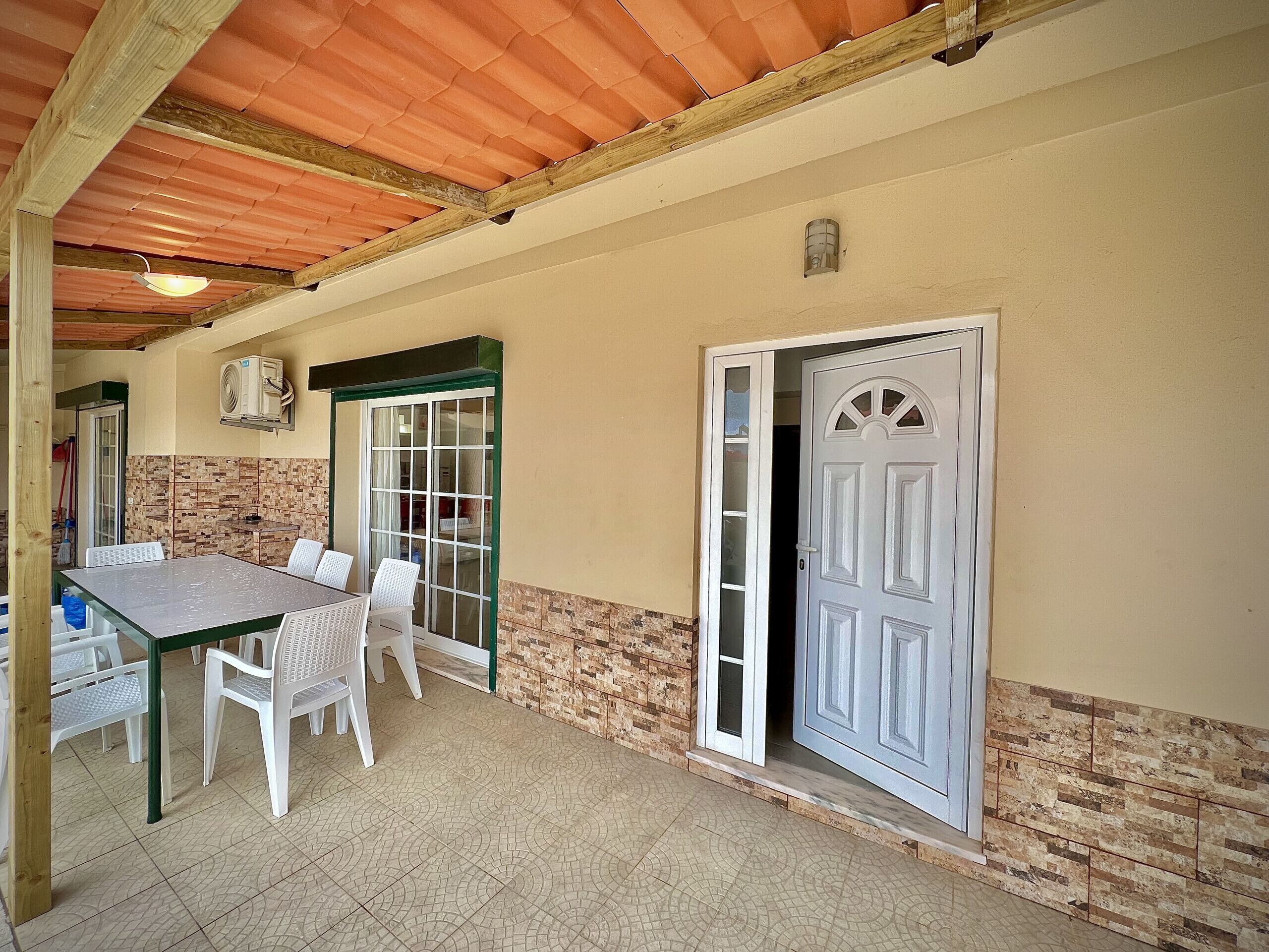 An outdoor patio area with a table and chairs, a sliding glass door, and a white door.