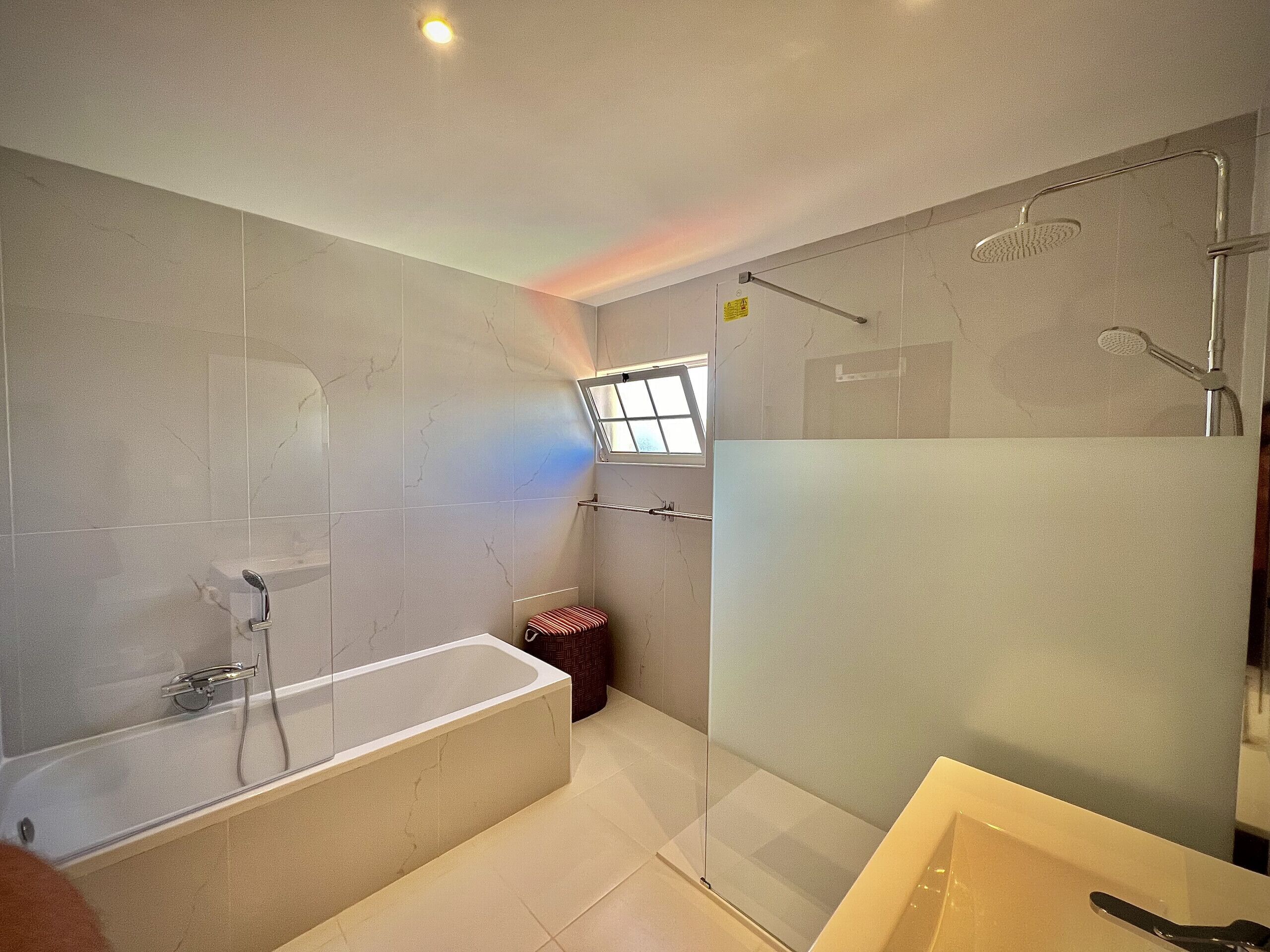 A modern bathroom with a bathtub, shower, and glass-enclosed shower area.