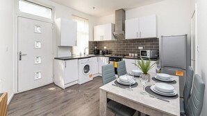 A compact kitchen with white cabinets, a built-in oven, and a microwave. - Leeds Contractor Home | Parking | Yorksha Property (Stanningley)