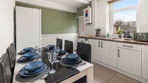 A modern kitchen with white cabinets, a built-in oven, and a window overlooking a garden.