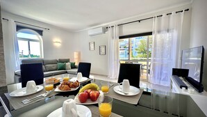 Ein modernes Hotelzimmer mit Essbereich, einer Couch und einem Fernseher.