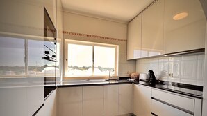 Eine moderne Küche mit weißen Schränken, einer schwarzen Arbeitsplatte und einem Fenster mit Blick nach draußen.