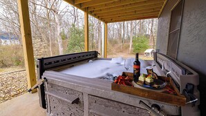 Ein Whirlpool mit Holzterrasse, einer Weinflasche und einer kleinen Figur am Rand.