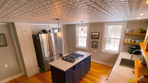 A modern kitchen with a central island, stainless steel appliances, and wooden flooring.