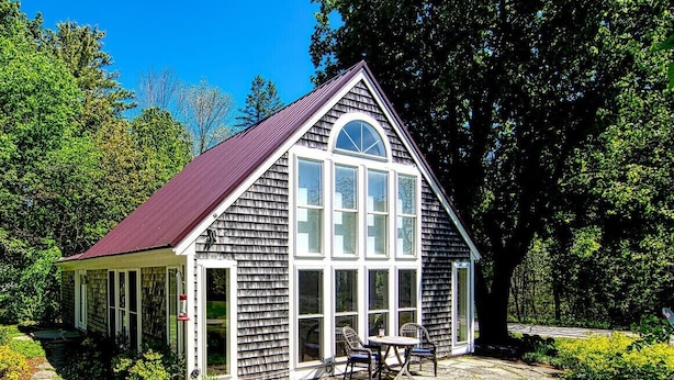 A small, single-story house with a gabled roof and large windows.