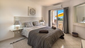 A bedroom with a bed, bedside lamps, a headboard, a window with curtains, and a view of the outdoors.