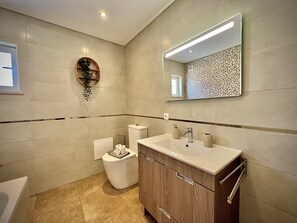 Et moderne badeværelse med toilet, vask og spejl.