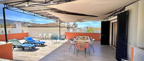 Une terrasse sur le toit dotée d’un espace salon couvert, d’une table de billard et d’une table à manger avec des chaises.