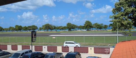 A parking lot with several cars, a track field, and a clear sky.
