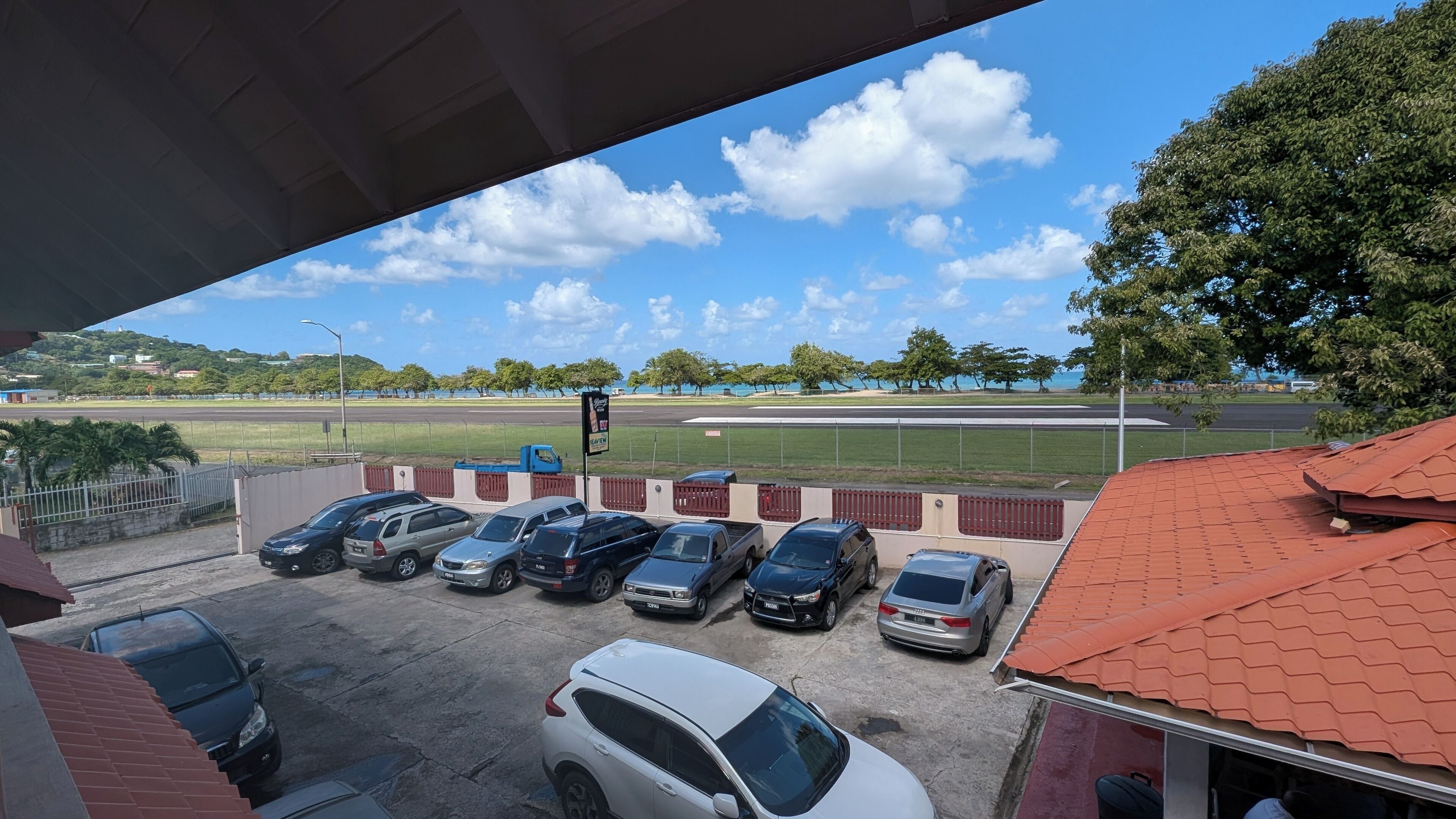 Un espace de stationnement avec plusieurs voitures, un terrain de sport et un ciel dégagé.