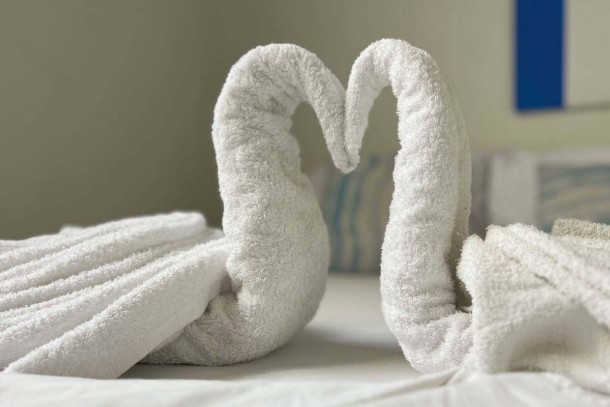 Una cama con toallas blancas dispuestas en forma de cisne.