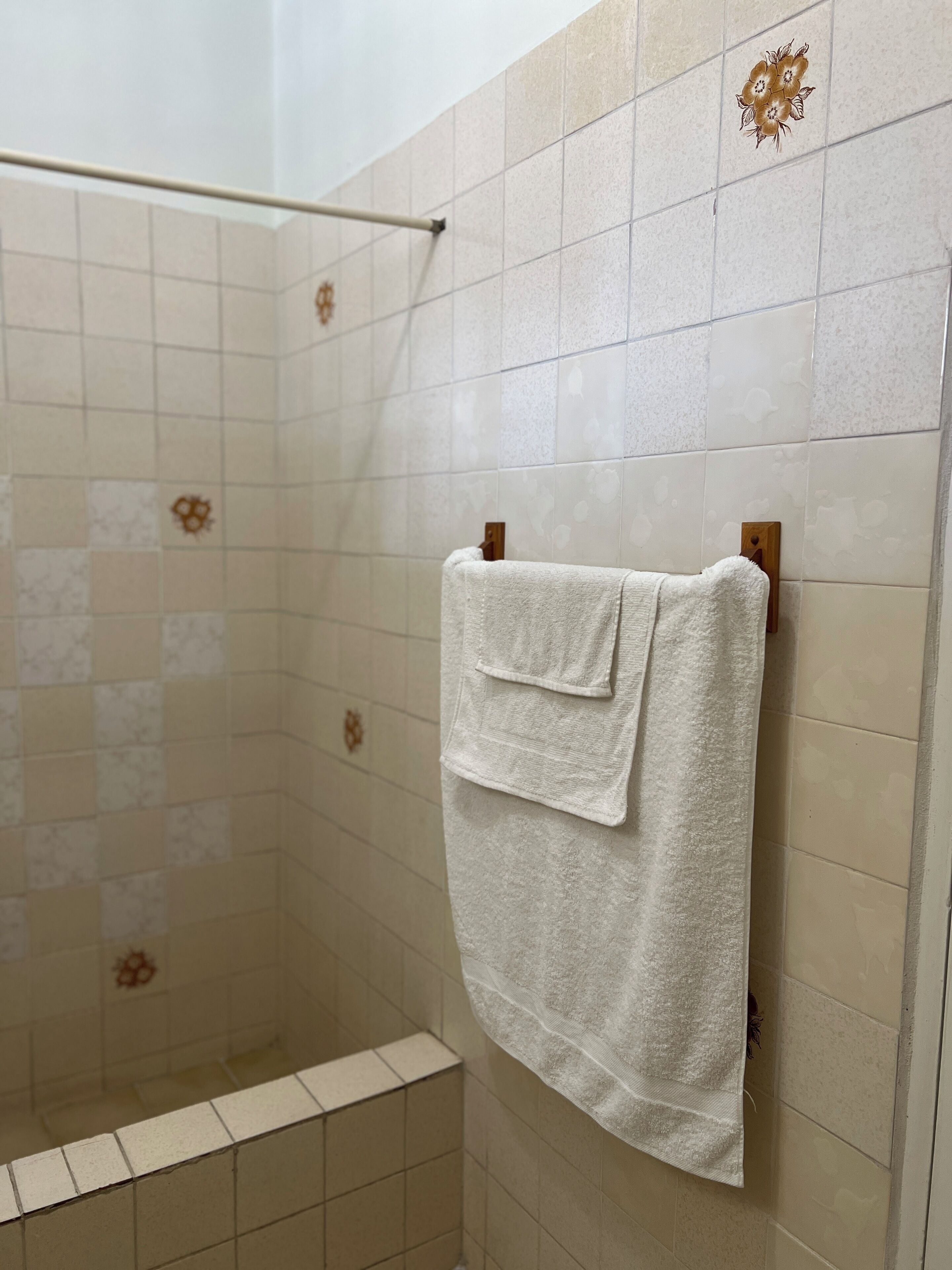 A shower area with beige tiles and a towel hanging on a rack.