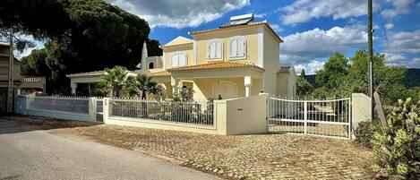 A two-story house with a white fence, a paved driveway, and a garden.