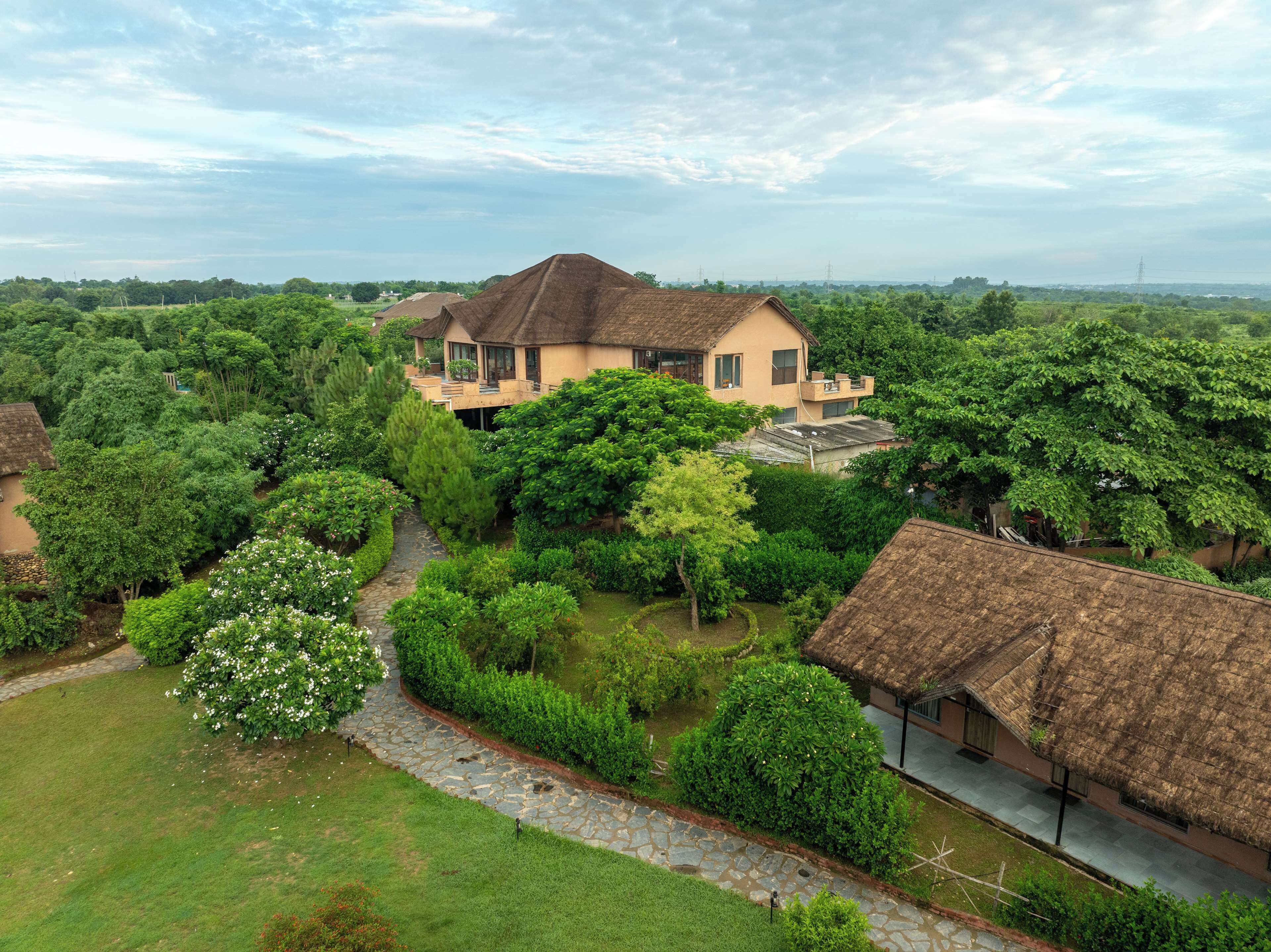 A large house surrounded by lush greenery and a stone pathway.