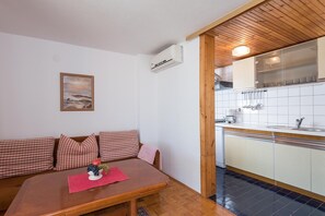 Cozy living space with a kitchenette, dining table, and sofa, featuring a coffee maker and a framed picture.