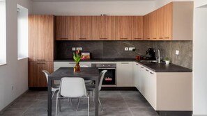 Modern kitchen with light cabinetry, dark countertop, and central island featuring a sink and small oven.