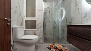 Bathroom features a toilet, shower, and vanity with a rug.