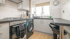 A modern kitchen with a built-in oven, a washing machine, and a sink. - Luxury Apt with 2 bathrooms n Free Parking (West Bromwich)