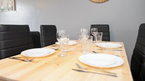 A dining table set with plates, glasses, and cutlery, surrounded by black upholstered chairs. - Luxury Apt with 2 bathrooms n Free Parking (West Bromwich)
