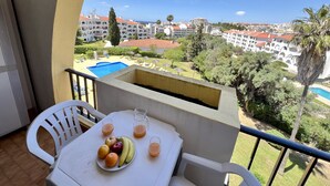 Un balcone con tavolo apparecchiato per la colazione, una piscina e vista su una zona turistica.