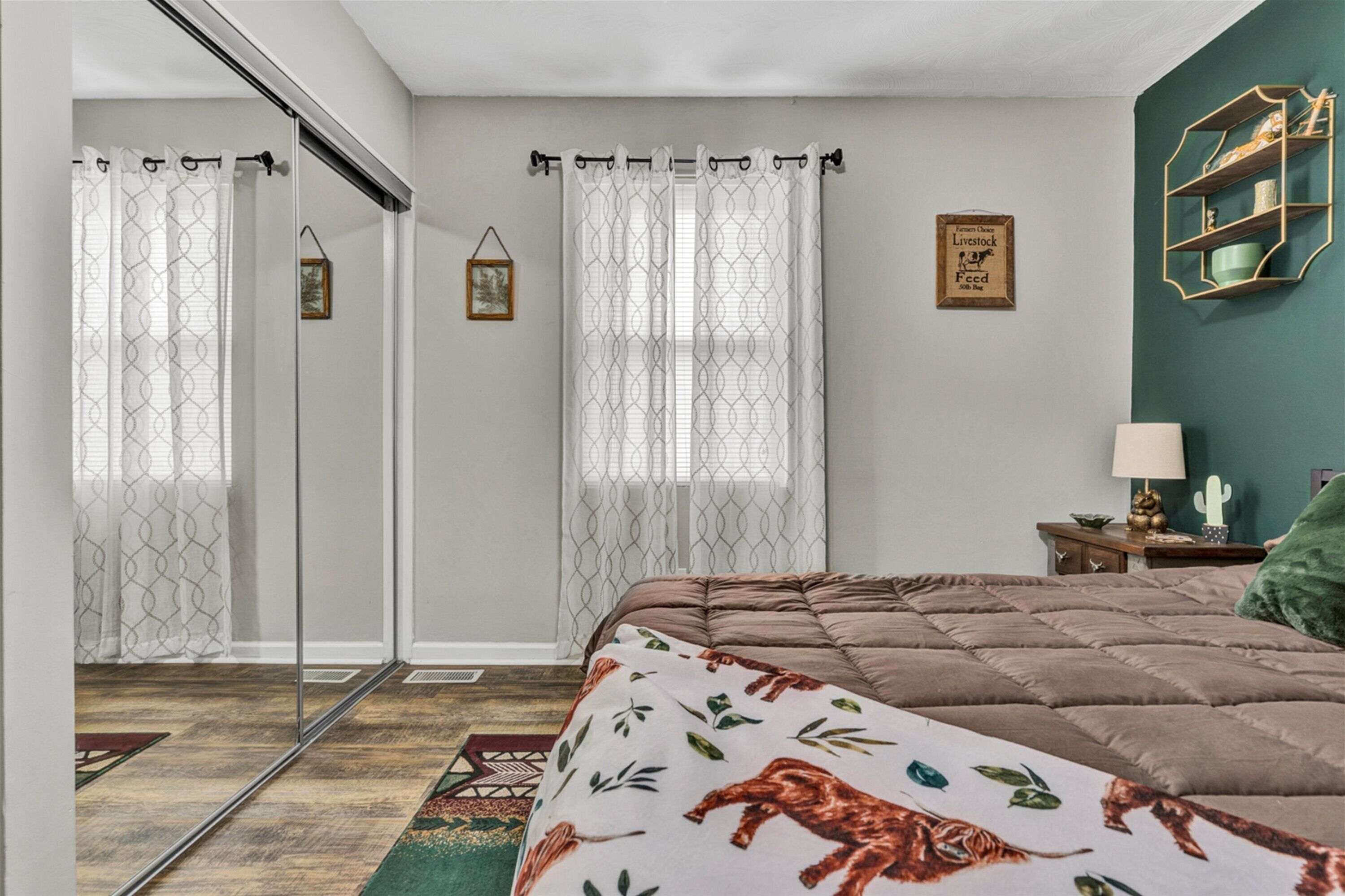 Une chambre avec un grand lit, une porte-fenêtre coulissante et un mur d’accent de couleur verte.