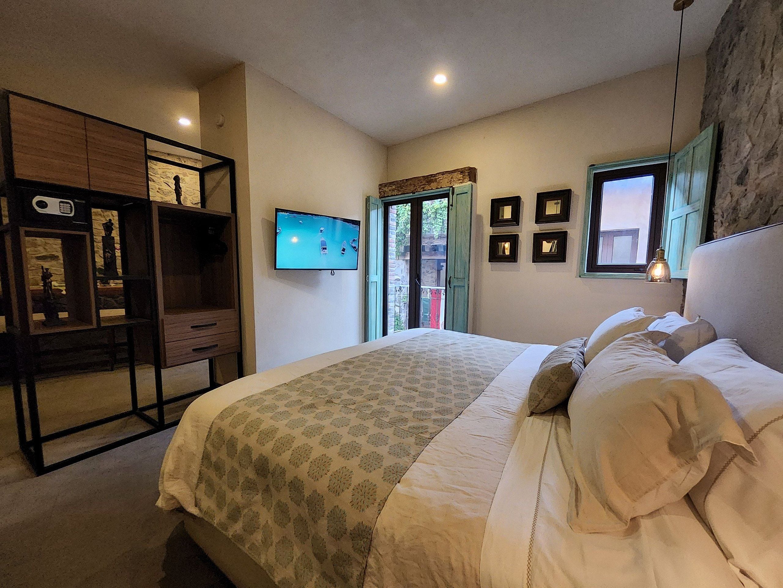 Quarto com cama, televisão, escrivaninha e janela.