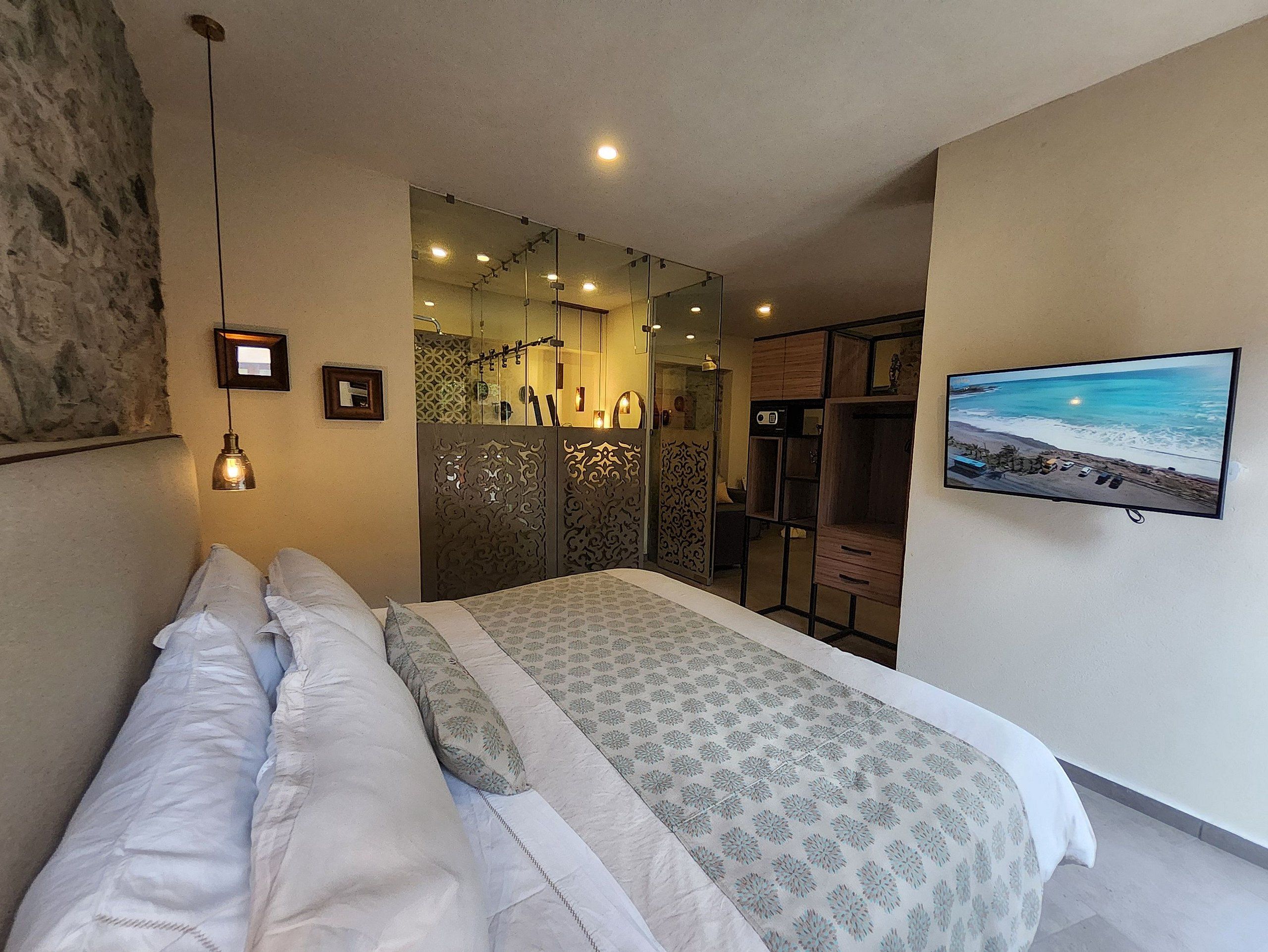 A bedroom with a bed, a television, and a view of the beach.