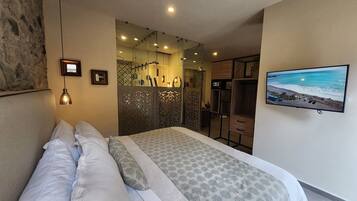 A bedroom with a bed, a television, and a view of the beach.