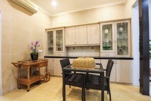 A kitchen with a dining table, chairs, cabinets, and a decorative cart with flowers. - Kota Damansara ICozy Cove Homestay 10 Pax (Petaling Jaya)