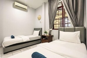 A hotel room with two beds, a bedside table, a lamp, a window with curtains, and an air conditioning unit. - Kota Damansara ICozy Cove Homestay 10 Pax (Petaling Jaya)