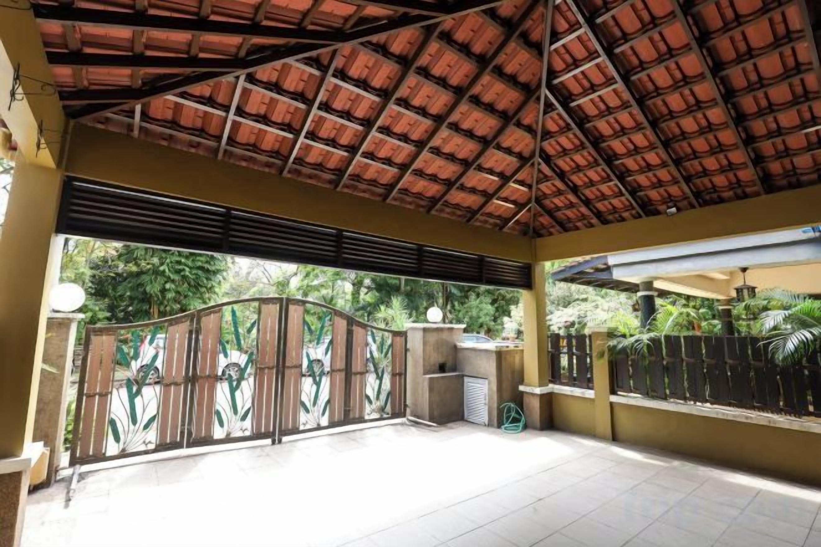 A covered outdoor area with a tiled floor, a metal gate, and a concrete wall.
