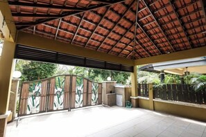 Un espacio al aire libre cubierto con suelo de baldosas, una reja metálica y un muro de hormigón.