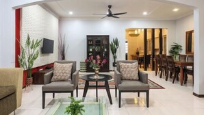 A modern living room with two sofas, a coffee table, and a dining area with wooden chairs and a table.