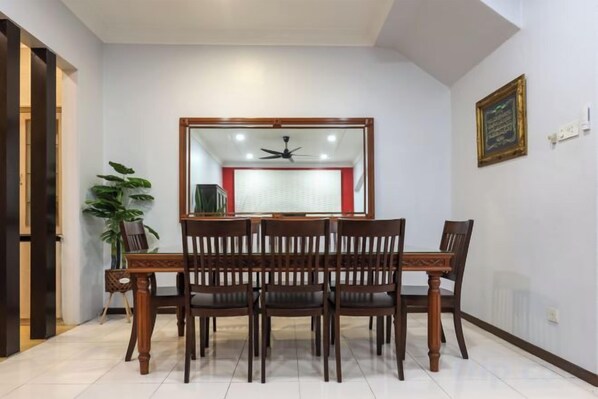 A dining area with a wooden table and chairs, a ceiling fan, and a large mirror on the wall. - Kota Damansara ICozy Cove Homestay 10 Pax (Petaling Jaya)