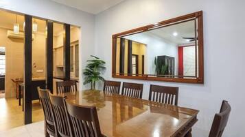 A dining area with a wooden table and chairs, a large mirror on the wall, and a potted plant.