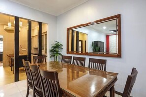 A dining area with a wooden table and chairs, a large mirror on the wall, and a potted plant. - Kota Damansara ICozy Cove Homestay 10 Pax (Petaling Jaya)